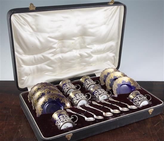 An Edwardian cased set of six Aynsley blue and gilt porcelain coffee cans and saucers with silver holders and spoons,